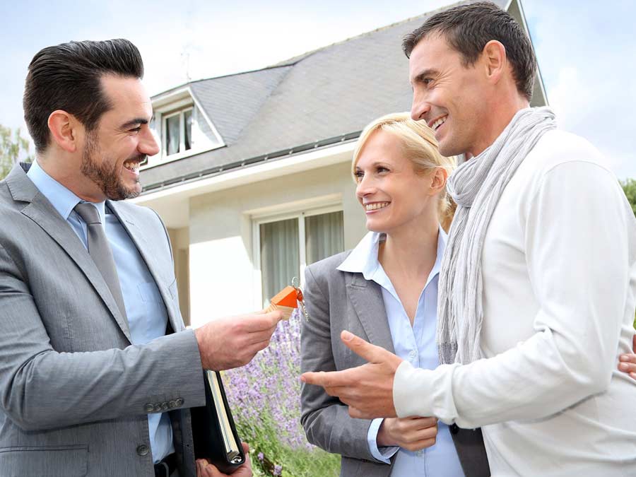 Real estate agent giving keys to a new home to a happy couple